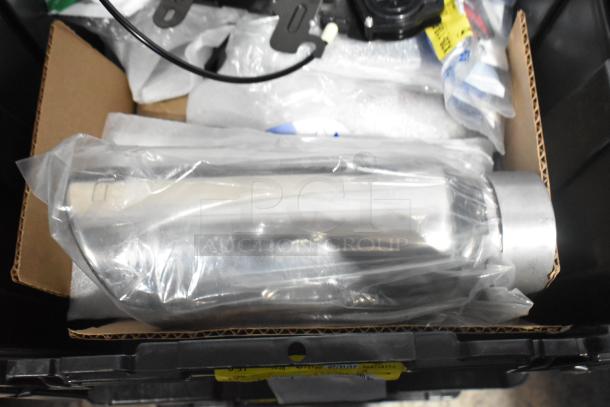 Brand new lot of car parts in a black poly bin, includes emblem and pouches, parts wrapped and unopened.