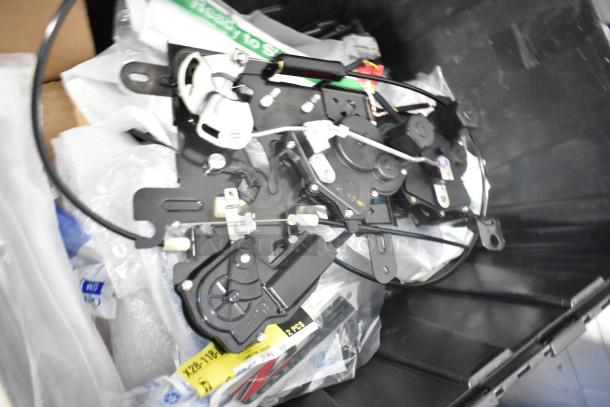 Brand new assorted car parts, including emblems and pouches, in a black poly bin, ready for use or resale.