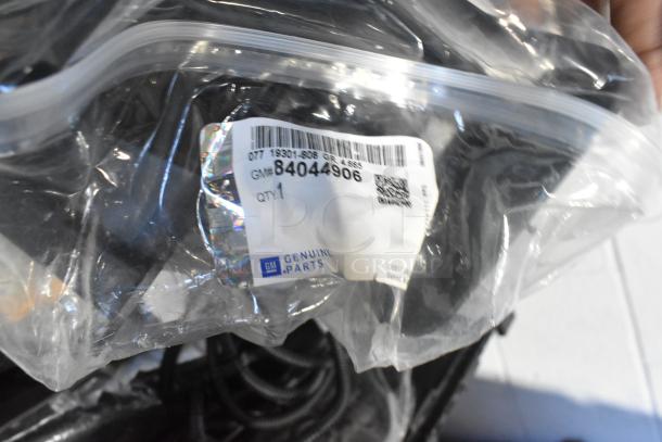 Brand new GM 84044906 brake deflector, labeled in a clear poly bag, part of car parts lot in black poly bin.