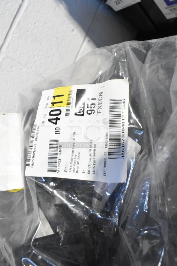 Brand new car parts, including GM 84044906 brake deflector, packaged in a black poly bin with a shipping label attached.