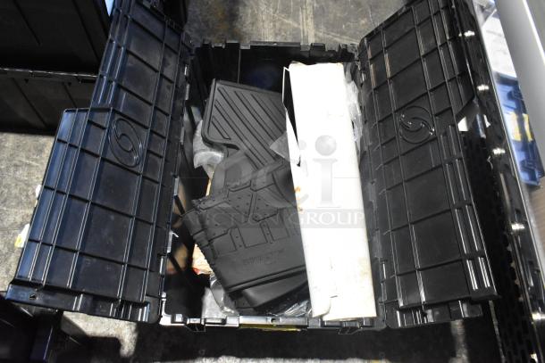 Brand new lot of car parts in a black poly bin, including black car mats. Bin lid open, showing contents.