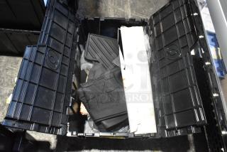 Brand new lot of car parts in a black poly bin, including black car mats. Bin lid open, showing contents.