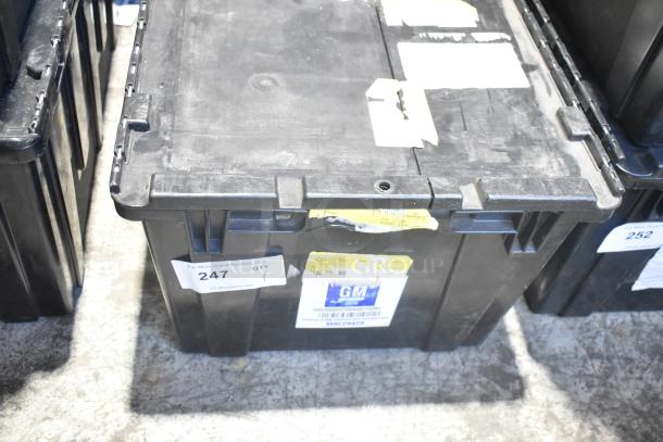 Black poly bin containing brand new car parts, including car mats. Labels on the bin indicate GM association and auction information.