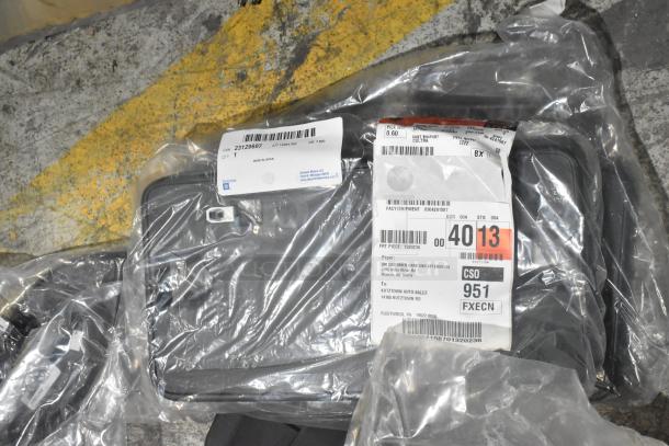 Brand new assorted car parts in black poly bin, includes car mats. Labels show Genuine GM Parts, made in Japan.