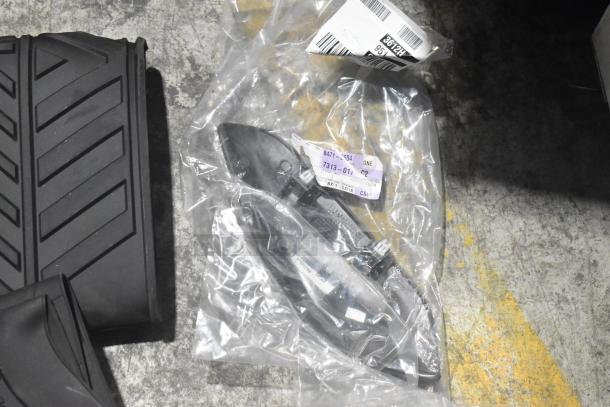 Brand new lot of car parts including black car mats, packaged in a poly bin. Visible labels show part numbers and shipping info.