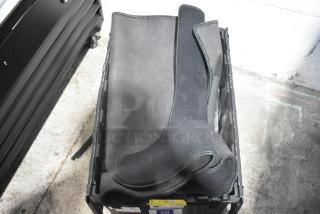 Brand new lot of various car parts in a black poly bin, featuring black car mats and an emblem.