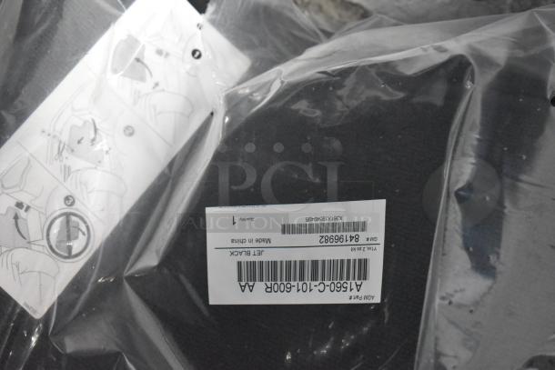Brand new car parts lot in black poly bin; includes car mats with labels showing barcodes and "Jet Black" description.