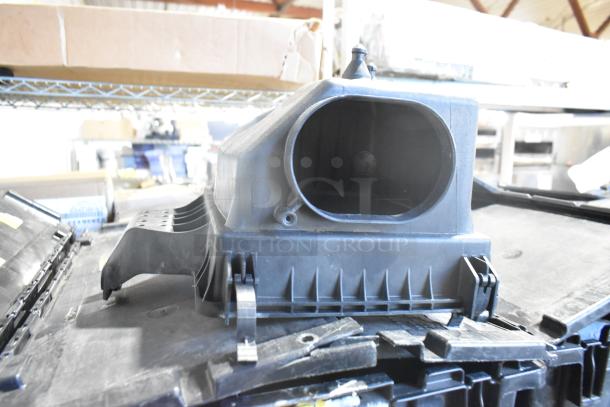 Brand new car part in black poly bin, featuring various components. Includes durable car mats.