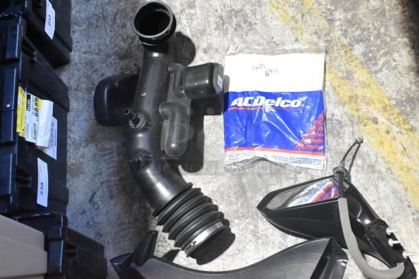 Brand new car parts in black poly bin, includes side view mirror and AC Delco packaged part, multiple items shown.