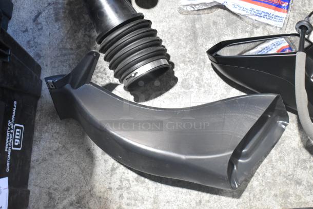 Brand new car parts, including black side view mirror and hose, in a poly bin. GM label visible.