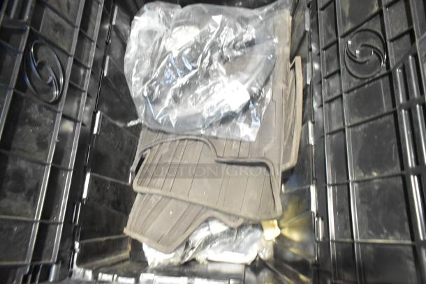 Brand new car parts in black poly bin, including car mats. Items appear in original packaging, showcasing clean, unused condition.