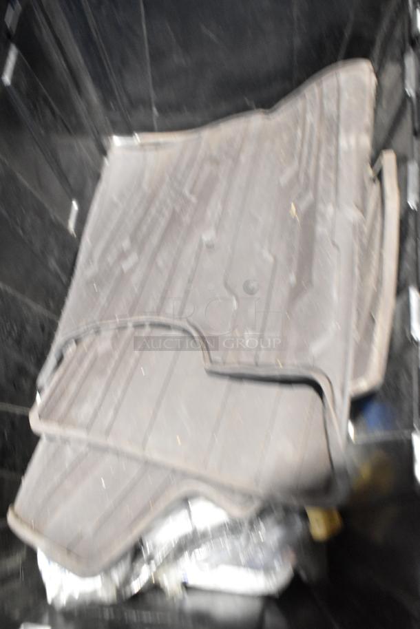 Brand new car parts including black car mats in a poly bin; protective and durable material.