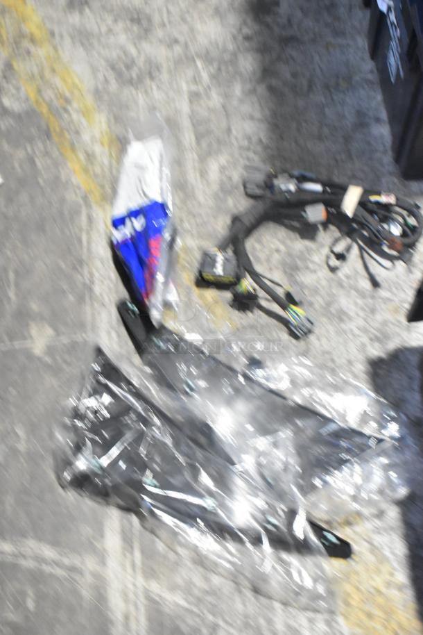 Lot of brand new car parts including filters and panels, wrapped in plastic, placed in a black poly bin.