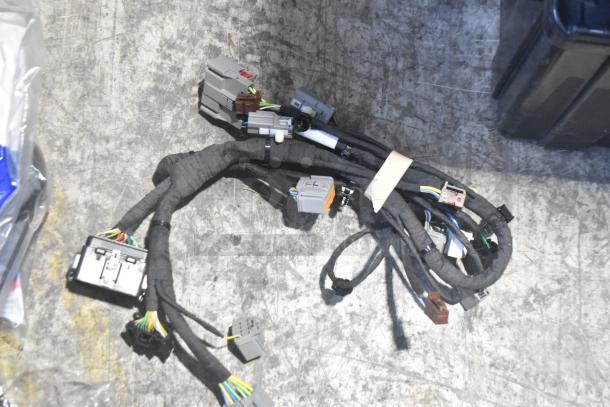 Lot of new car parts, including wiring harnesses, in black poly bin. Ideal for automotive repairs.