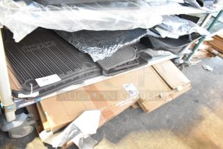 Brand new tier lot of car parts including black car mats, boxed and wrapped. Features tags and labels indicating new condition.