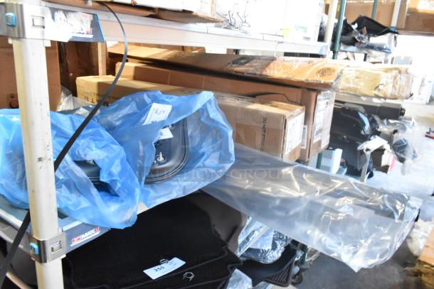 Brand new tier lot of car parts, featuring a GM 20862098 mirror assembly, labeled and packaged, ready for auction.
