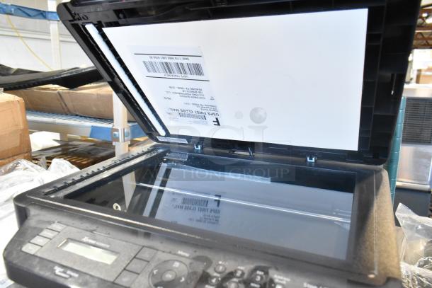 Samsung Xpress M2885FW printer, copier, scanner. Open scanner lid with document. Keypad visible. Good condition.