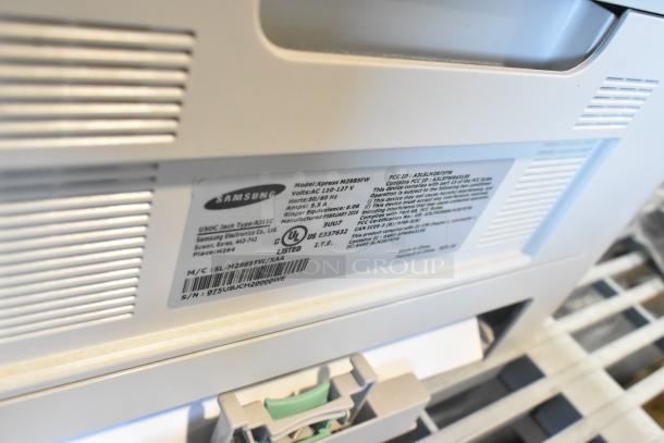 Samsung Xpress M2885FW printer with visible model tag, showing details like voltage and certifications; good condition.