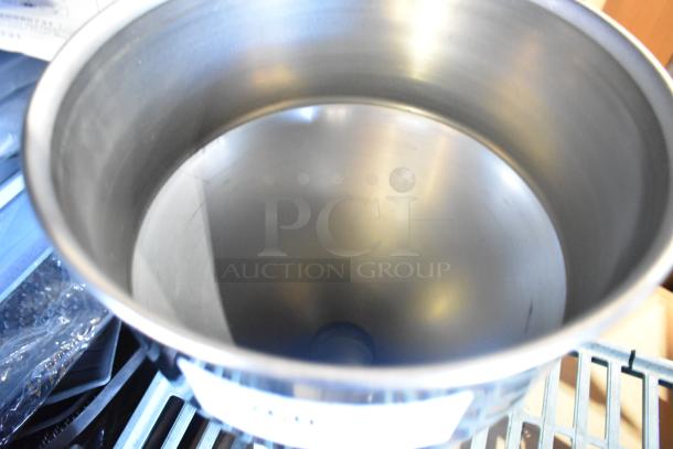 Stainless steel metal hopper with smooth interior, cylindrical shape, and visible rim; appears in excellent condition.