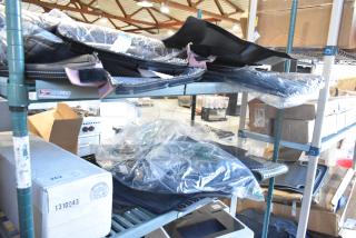 Two-tier shelving with brand new car mats in plastic wrapping, displaying various items and boxes.