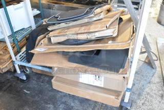 Two-tier lot of brand new items, including car mats, stacked on a cart. Items are unopened in original packaging.