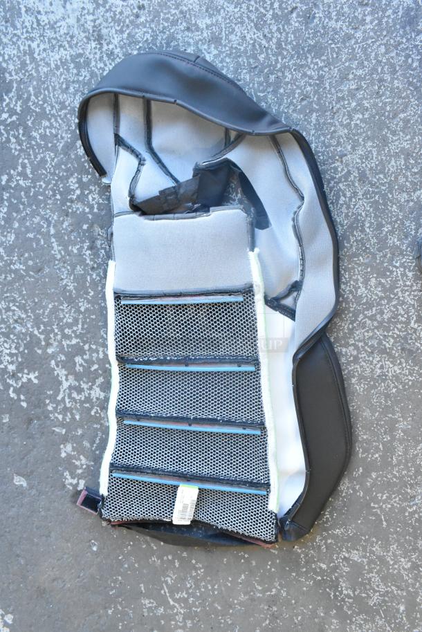 Brand new car mat with mesh design and foam backing, gray and black color, includes manufacturer tag.
