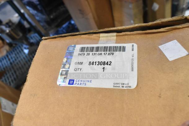 Box labeled "GM Genuine Parts" with GM# 84130842. Contains new auto parts including bumper, spoiler kit, window deflector.