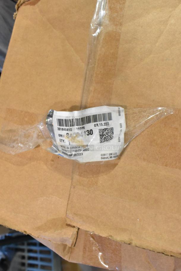 Cardboard box with a GM label including part number 84004130. Box contains new GM auto parts like a front bumper and spoiler kit.