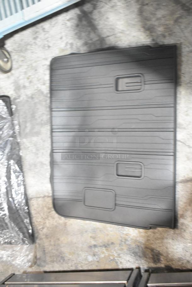 Brand new black car mat with raised grooves, part of a tier lot. Rugged design, durable material, no visible wear.