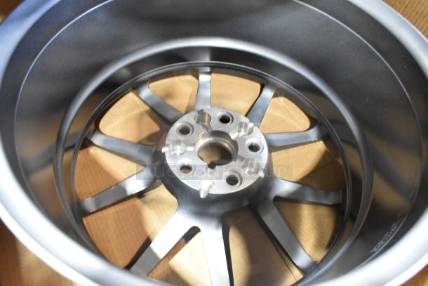 Brand new box containing two metallic rims, shown in pristine condition, with multi-spoke design and smooth finish.