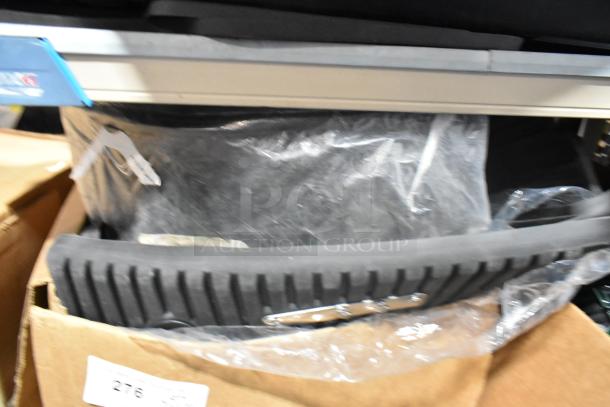 Brand new tier lot of various items in box, featuring black car mats in protective plastic packaging. 