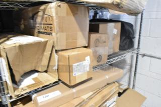 Tiered shelf with unopened boxes, including GM 84162521 new third row all-weather rubber floor mat in black.