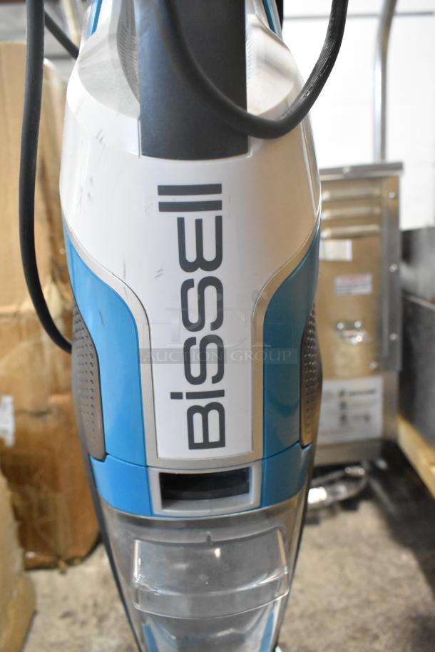 Bissell Multi Surface Brush Vacuum Cleaner, 115V, 1 Phase, blue and gray, with visible scratches, standing on concrete.