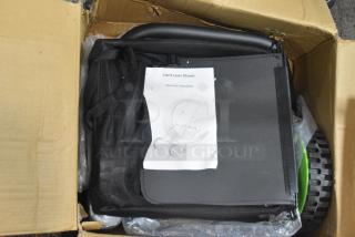 Brand new hand lawn mower in a box with assembly instructions. Features black handle and green wheels.