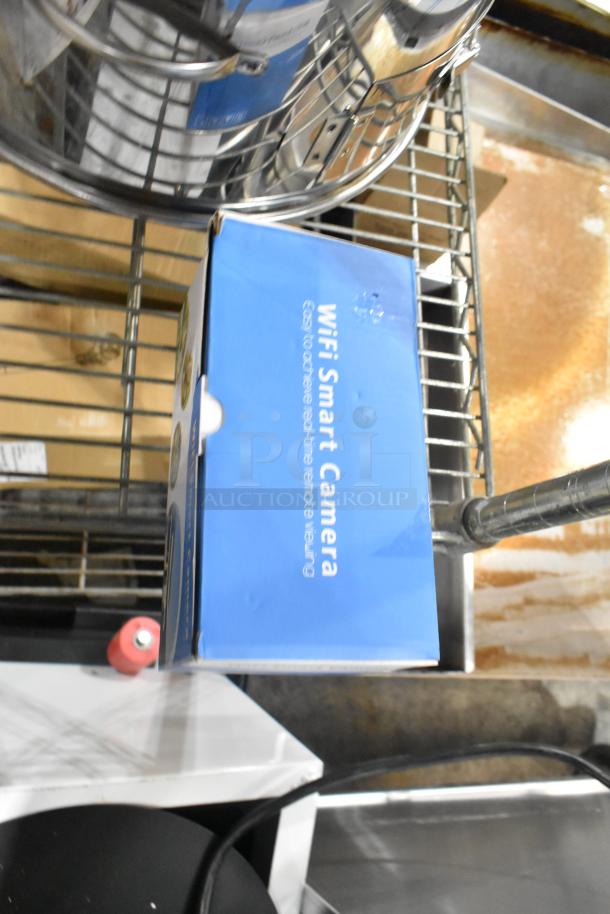 Box of WiFi Smart Camera labeled for real-time remote viewing, part of a scratch and dent auction bundle.