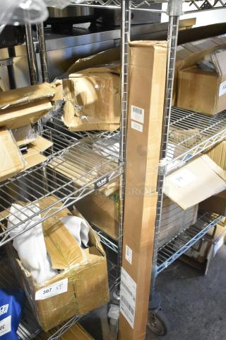 Boxes with minor damage on metal shelf containing a brand new heavy duty spring loaded gate caster and cordless cellular shades. Tags show inventory labels.