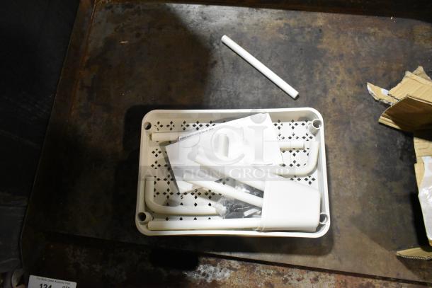 Brand new scratch and dent items: Juice dispenser and white cart parts on a rustic surface, includes paperwork and packaging.