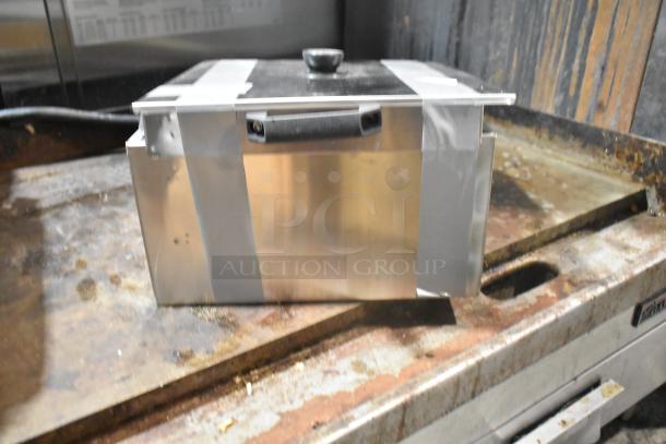 Brand new metal bin with dents, tape securing lid. Ideal for storage, industrial setting. Some scratches visible.