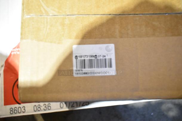 Cardboard box with barcode label, possibly containing a mix of new scratch and dent items like food trays, wooden barrel decor, and a jar.