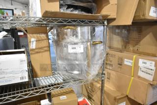 Brand new stainless steel round chafer with minor scratches, wrapped in plastic. Features gold-tone handles. Item tag 328 visible.