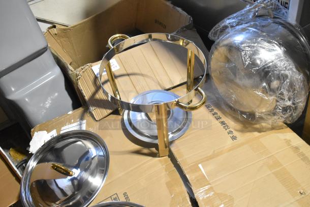 Brand new stainless steel round chafer with gold-toned handles, slight scratches and dents visible, includes lid and frame.