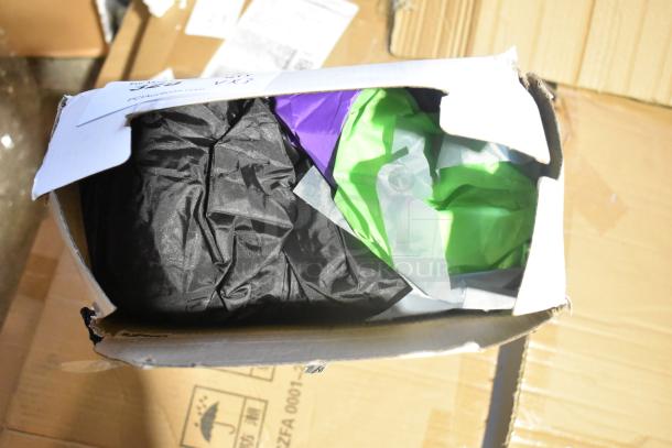 Box containing new, scratch and dent items, including an inflatable witch decoration. Various colors visible: black, purple, green.