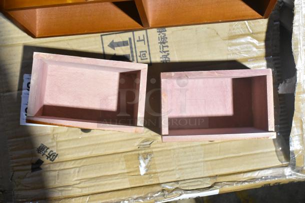 Two pink wooden boxes on cardboard, part of scratch and dent auction items, appear new with slight surface wear.