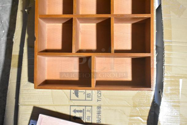 Wooden organizer with multiple compartments, minor scratches on edges, placed on cardboard box with handling symbols.