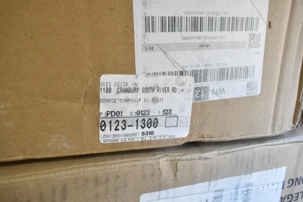 Cardboard box with labels, including an address from Oakes Decor Inc, indicating new items with scratch and dent.