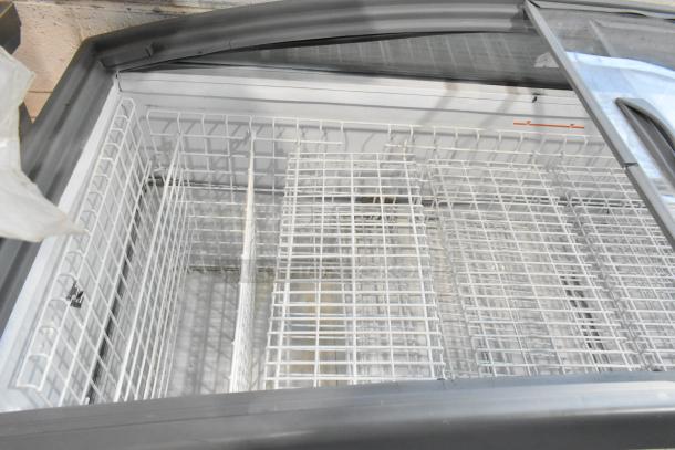 Metal commercial freezer merchandiser with glass top, spacious wire shelving, on commercial casters, in good condition.