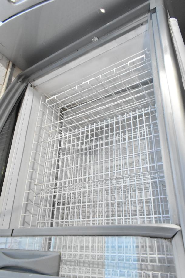 Metal commercial freezer merchandiser with white wire shelves and clear doors, on commercial casters, in excellent condition.