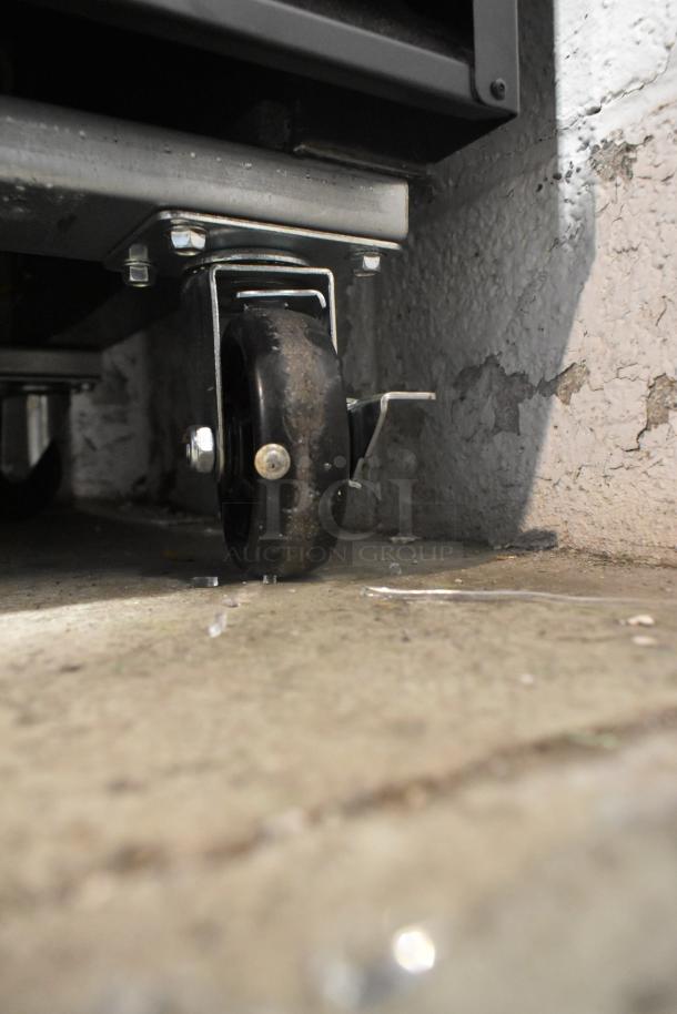Close-up of a commercial caster wheel on the Avantco 178GDC40HCB cooler. Note broken glass nearby. Brand new, scratch and dent.