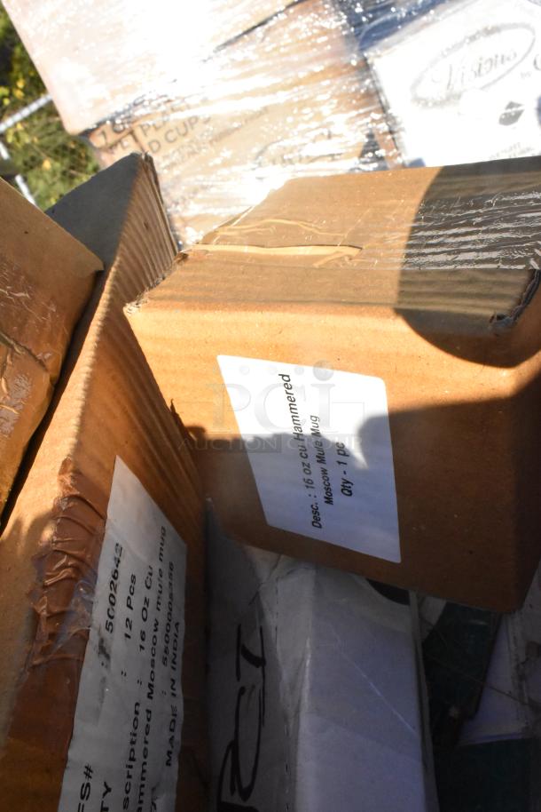 Boxes labeled "16 oz Hammered Moscow Mule Mug" stacked among other packaged items, some shrink-wrapped.