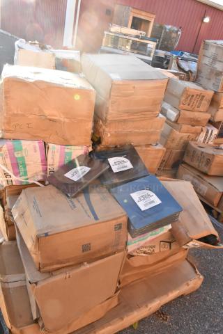 Cardboard boxes stacked outdoors, containing brand new scratch and dent items like cups, containers, and napkins. Some boxes partially open.